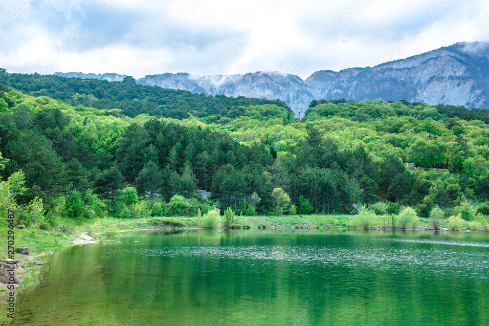 The lake with emerald water is surrounded by coniferous forests and mountains. The concept of ecological and active tourism.