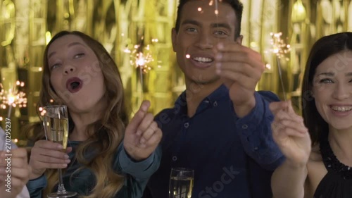 Wallpaper Mural 4 happy cheerful people at a party light a sparkler. a group of laughing people of mixed race on a gold background. HD Torontodigital.ca