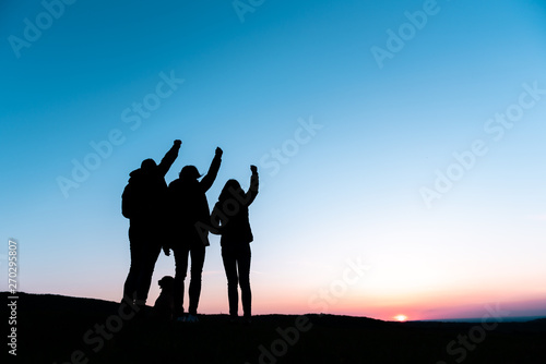 Family with dog standing at hill with arm raised