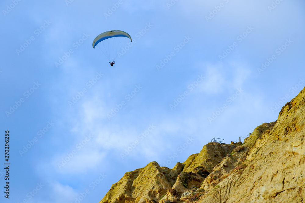 Man doing sport (Para-glider). Man paragliding in the clouded sky. Paragliding is an extreme sport and recreation. Torrey Pines Gliderport. San Diego. California, USA. Man doing sport (Para-glider). Man paragliding in the clouded sky. Paragliding is an extreme sport and recreation. Torrey Pines Gliderport. San Diego. California, USA.