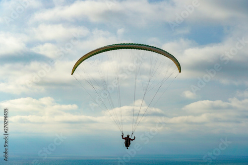 Man doing sport (Para-glider). Man paragliding in the clouded sky. Paragliding is an extreme sport and recreation. Torrey Pines Gliderport. San Diego. California, USA.