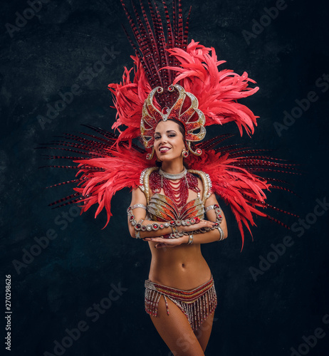 Szczęśliwy piękny tancerz Brasil w czerwonym kostiumie z piór tańczy na małej scenie.