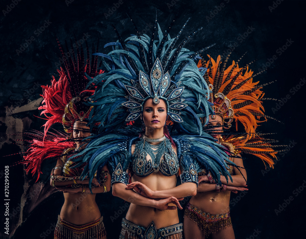 Fototapeta premium Three beautiful young womans in traditional brasilian carnaval costumes are posing for photographer at studio.
