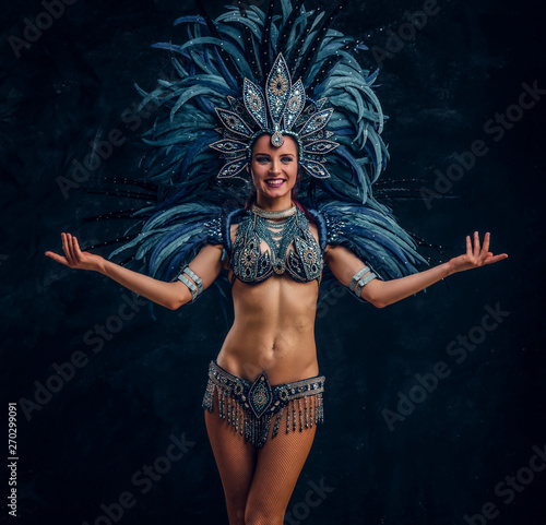 Happy brasil dancer is posing for photographer. She is wearing blue feather costume.