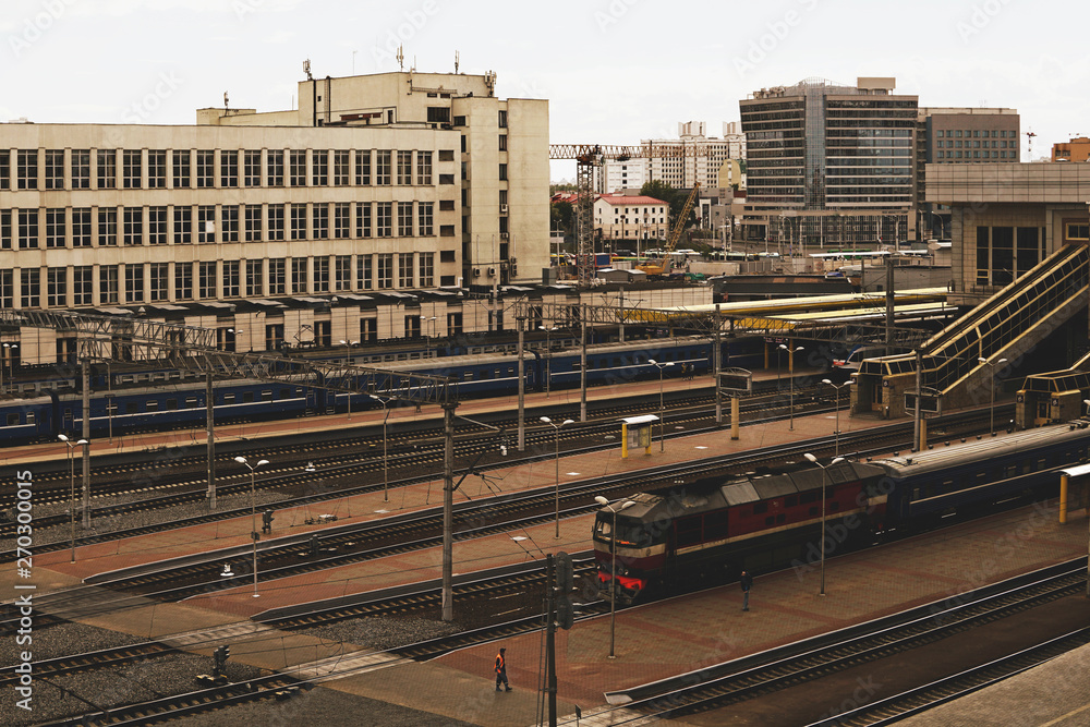 The train at the station, railway tracks, buildings on the background.