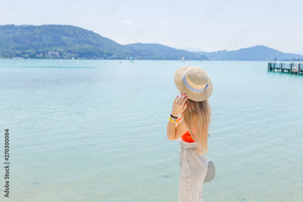 Back view of young woman in boater relaxing and admiring the vie