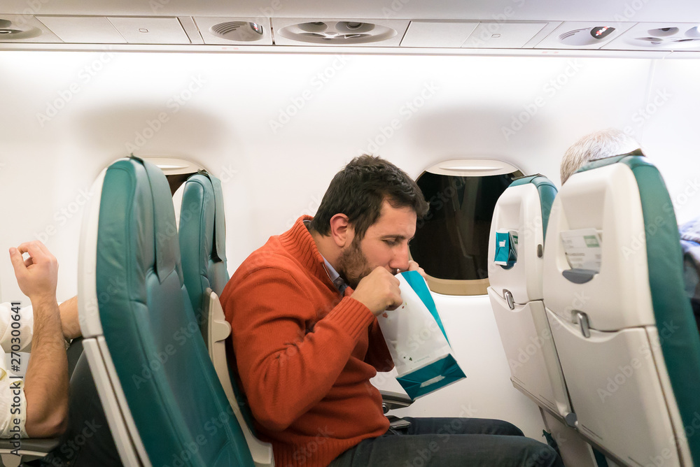 Airsickness. Man feels very bad on the air plane, using a sickness bag  (also known as a sick sack, emesis bag, barf bag, vomit bag) Stock Photo |  Adobe Stock