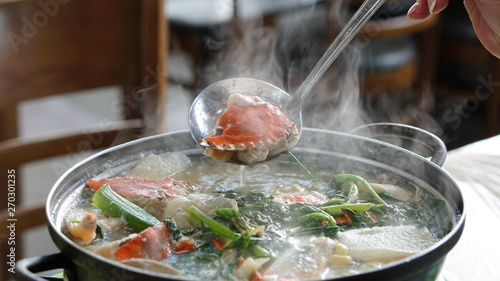Boiling seafood soup with shrimps, crabs, clams and vegetables cooked in Jagalchi fish market in South Korea in Busan.