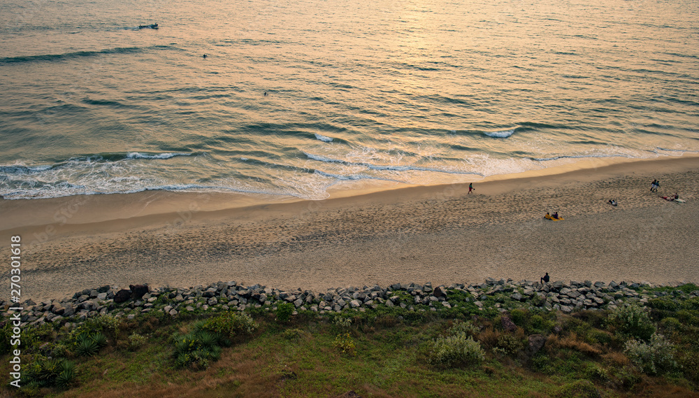 View from above, stunning aerial view of a beautiful tropical beach with people sunbathing and enjoying a beautiful sunset. Varkala, Kerala, India. View from above, stunning aerial view of a beautiful tropical beach with people sunbathing and enjoying a beautiful sunset. Varkala, Kerala, India.