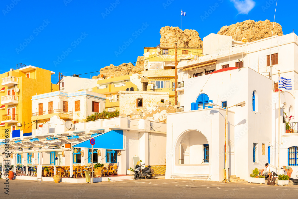 Whitewashed buildings in picturesque Pigadia port on Karpathos island at sunset time, Greece