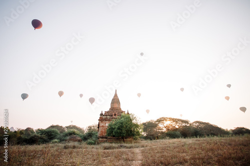 Hot air balloon over the foggy morning around Temple in Bagan, Myanmar. Balloons fly over thousands of ancient pagodas. Dawn in Bagan, misty. Tourists are watching the sunrise over the ancient city.