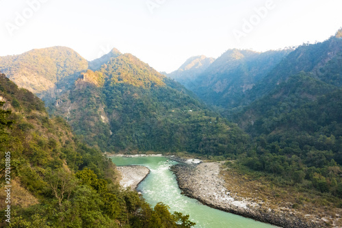 Stunning view of some green mountain peaks with the Sacred Ganges River flowing between them in Rishikesh, India.