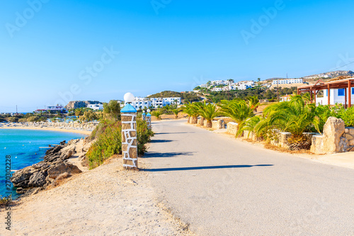 Coastal road with palm trees and colorful houses along beautiful sea at Ammopi beach  Karpathos island  Greece