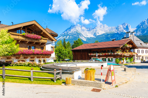 Traditional alpine houses on square in village of Going am Wilden Kaiser on beautiful sunny summer day with Alps mountains in background, Tirol, Austria