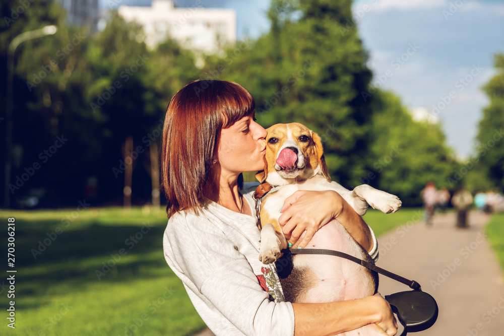 Portrait of young woman kissing her cute beagle dog. Love, happy, kissing puppy.
