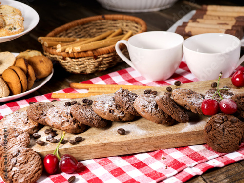 Wallpaper Mural Oatmeal chocolate cookies with coffee grains and cherry, powdered sugar on kitchen cutting board with checkered fabric on wooden table in village style for picnic. Problems with excess weight. Torontodigital.ca