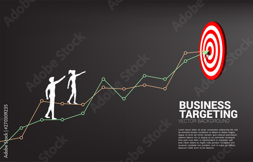 silhouette of businessman and businesswoman point to dartboard on line graph to center of dartboard. Business Concept of targeting and customer.route to success.
