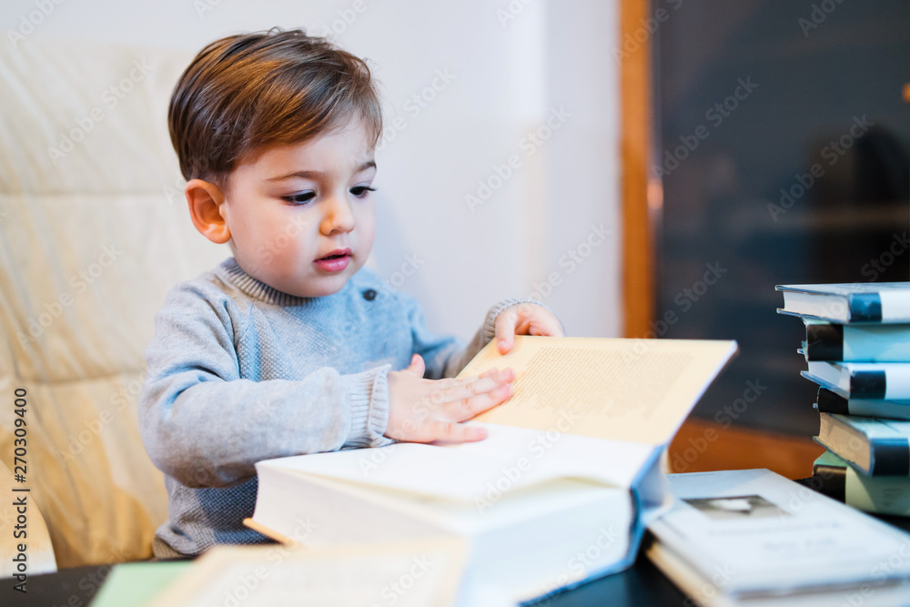 Small little boy playing with books at home seeking knowledge wisdom Small little boy playing with books at home seeking knowledge wisdom