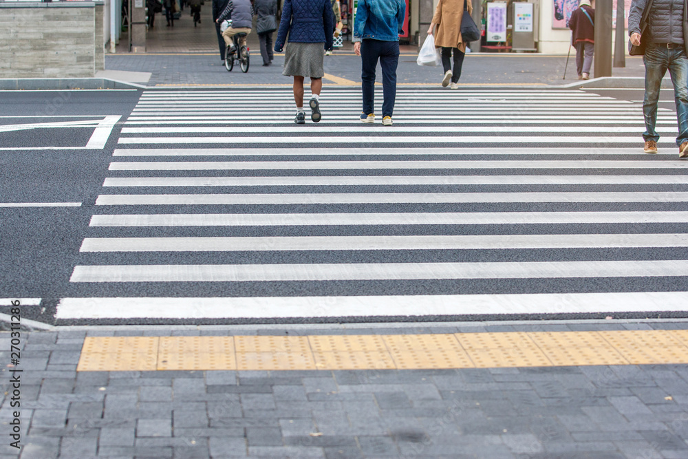 People in busy city are walking on the asphalt road on a safety crosswalk on background, Lifestyle in Japan