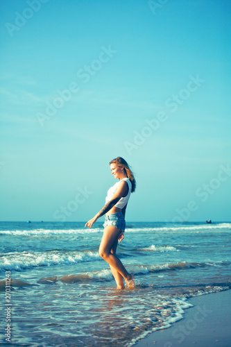 young pretty blond woman at seacoast walking relaxing, fashion lady at sunset, cool vacations