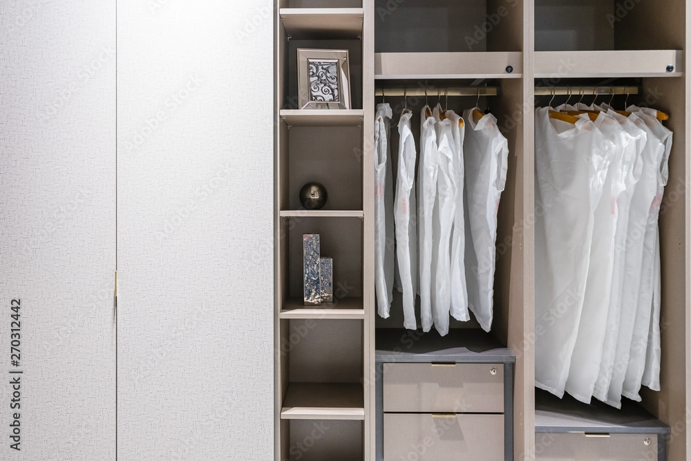 modern wooden wardrobe with women clothes hanging on rail in walk in closet, Scandinavian style