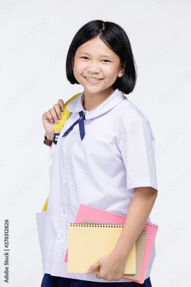 Cute girl in student's uniform with stationery on gray background. Cute girl in student's uniform with stationery on gray background.