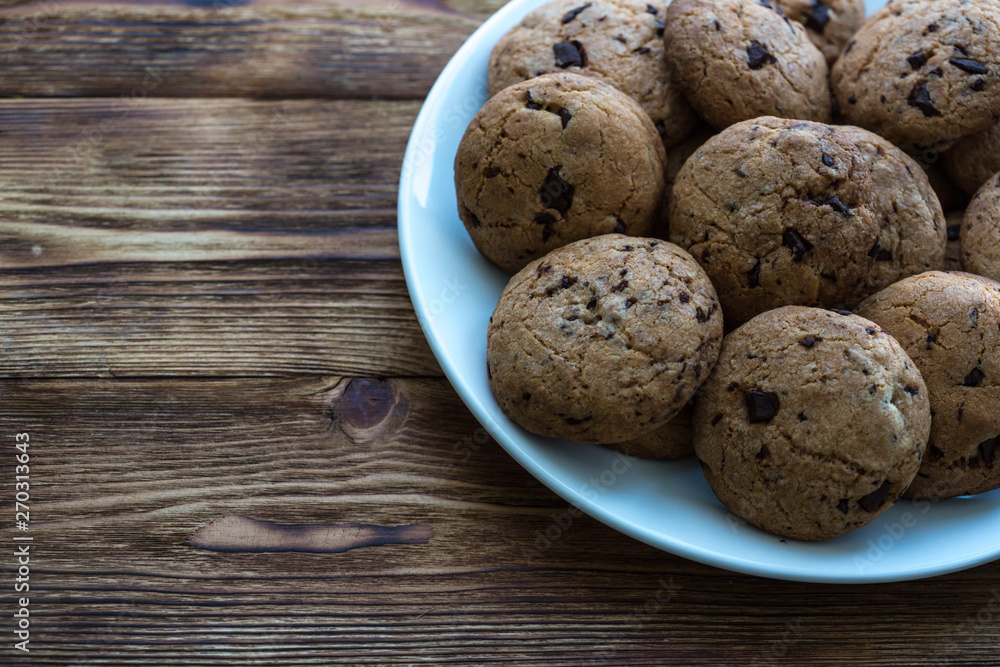 Pile of Delicious Chocolate Chip Cookies on a plate on wooden table Pile of Delicious Chocolate Chip Cookies on a plate on wooden table