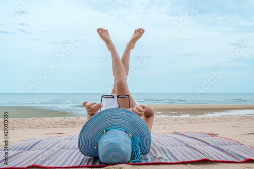 Fototapeta Naklejka Na Ścianę i Meble -  portrait of female with hat relaxing on beach mat by beach