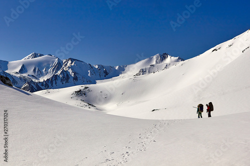 Bunch of mountaineers climbs walking along the glacier