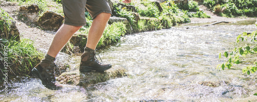 Fotografía Mann überquert fluss beim wander in wasserdichten lederschuhen