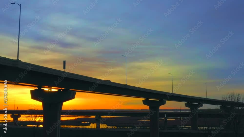 Morning rush hour traffic zooms past on elevated highway, colorful sunrise background, aerial drone cinematography. Morning rush hour traffic zooms past on elevated highway, colorful sunrise background, aerial drone cinematography.
