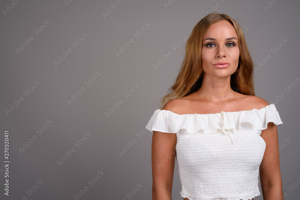 Young beautiful woman with blond hair against gray background Young beautiful woman with blond hair against gray background