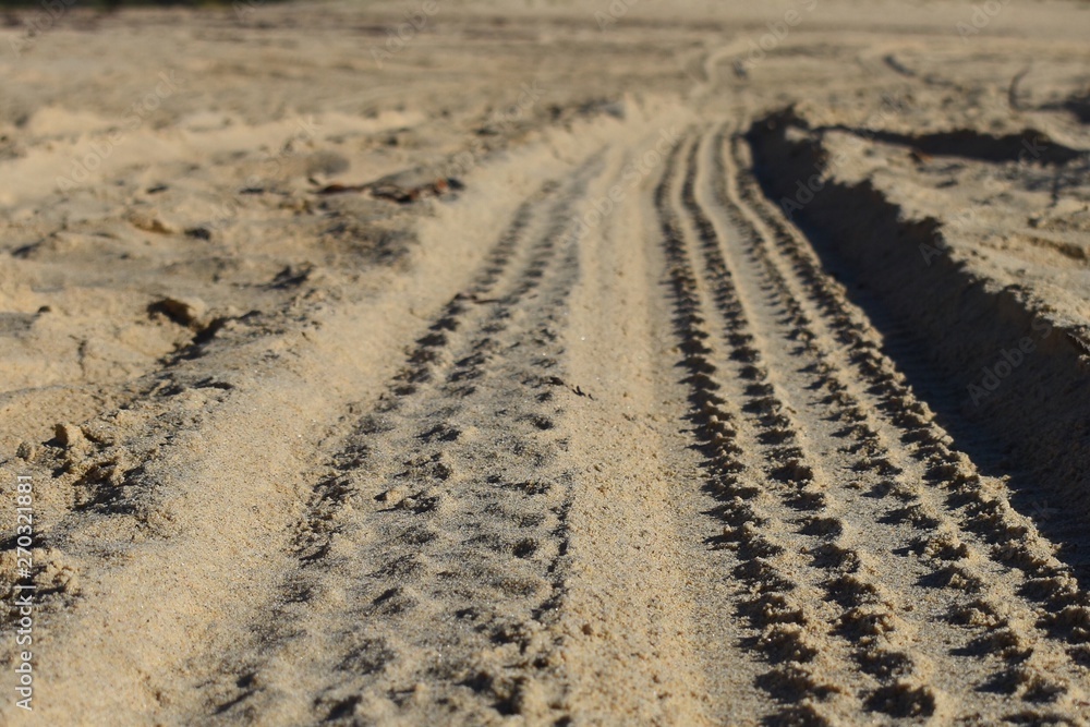 Four wheel drive tyre marks in soft sand at ground level background Four wheel drive tyre marks in soft sand at ground level background