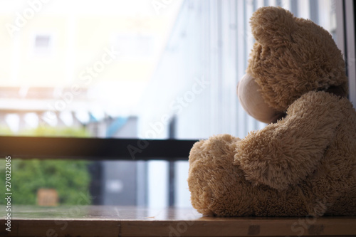 major depressive disorder mdd concept. Grief of children. Teddy bear sitting looking at the house window alone. Looks like someone who is sad, disappointed, depressed