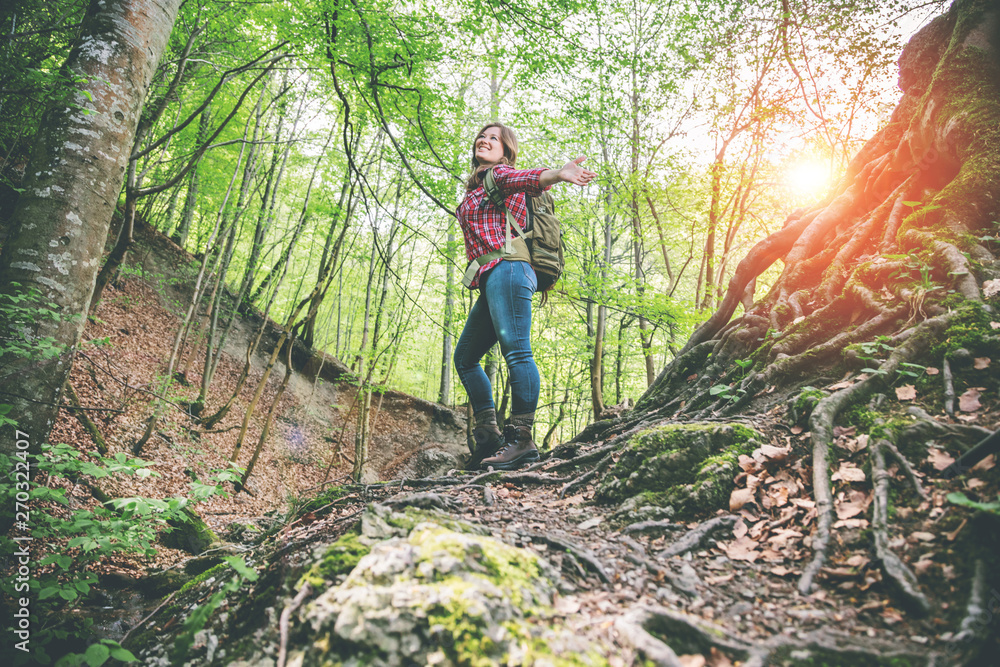 Fototapeta premium Frau mit rucksack in einem schönen wald beim wandern in der nähe eines wasserfalls