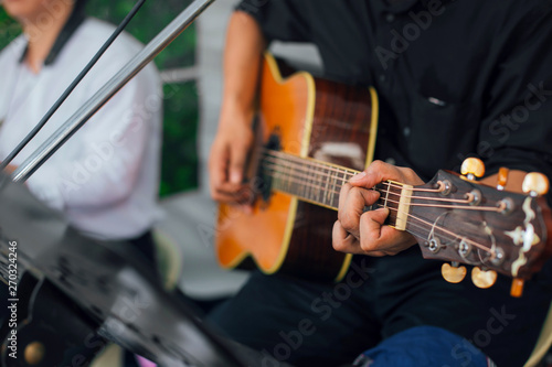 A Men's hand playing guitar with friends during the live performance on stage. Focus selection