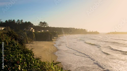 Waves rolling on shore at the Oregon coast near Coos Bay. Houses on cliff can be seen. photo