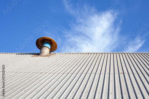 Exaustor de telhado em fábrica com céu azul photo