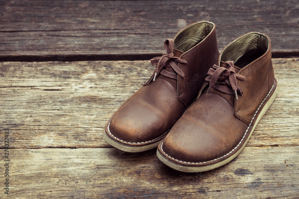 Brown stylish boots on wood background, retro color Brown stylish boots on wood background, retro color