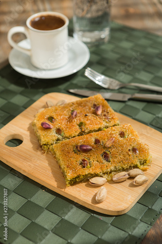 Traditional turkish and arabic dessert baklava with walnuts and pistachios Homemade  baklava on wooden plate and turkish cofffe served at bayram photo