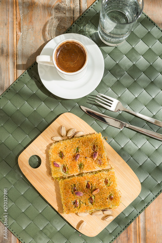 Traditional turkish and arabic dessert baklava with walnuts and pistachios Homemade  baklava on wooden plate and turkish cofffe served at bayram photo