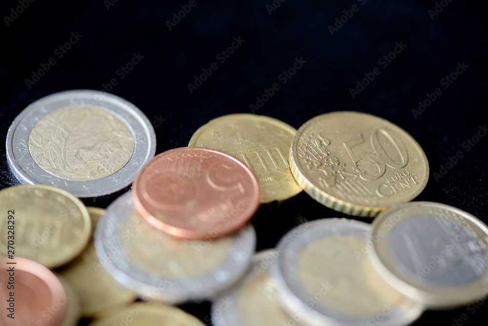 Pile of Euro coins scattered on a dark surface close up Pile of Euro coins scattered on a dark surface close up