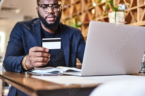 Know what you own, and know why you own it. African american businessman holds his credit card, while resting in the cafe