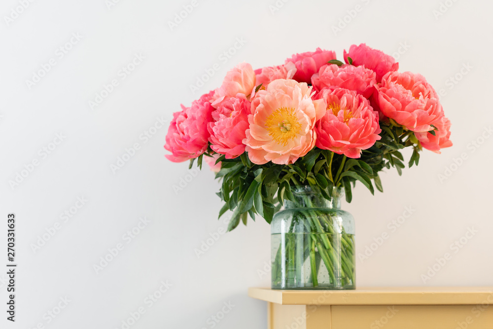 Coral peonies in a glass vase on wooden table.. Beautiful peony flower for catalog or online store. Floral shop concept . Beautiful fresh cut bouquet. Flowers delivery. Copy space Coral peonies in a glass vase on wooden table.. Beautiful peony flower for catalog or online store. Floral shop concept . Beautiful fresh cut bouquet. Flowers delivery. Copy space