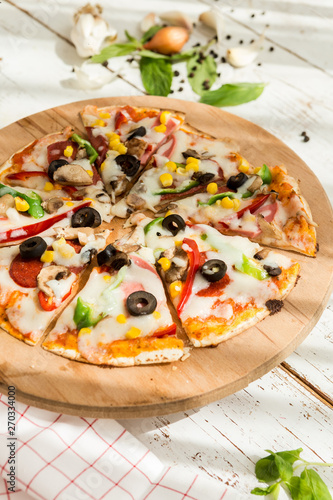 home made gourmet thin tortilla pizza on wooden plate and wood table gourmet food