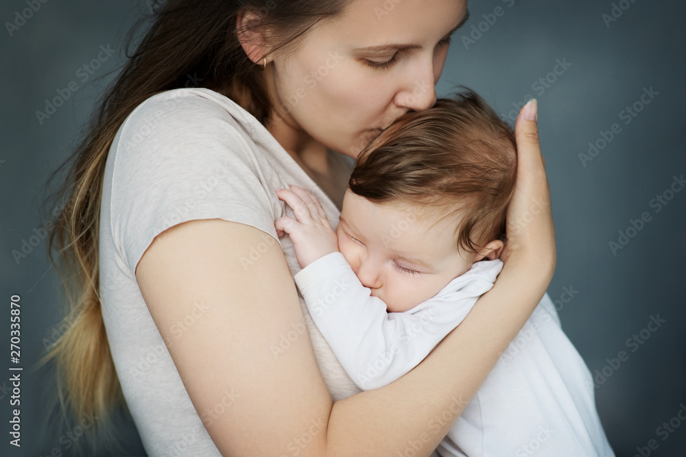 Young mother kissing her sleeping newborn baby. Young mother kissing her sleeping newborn baby.