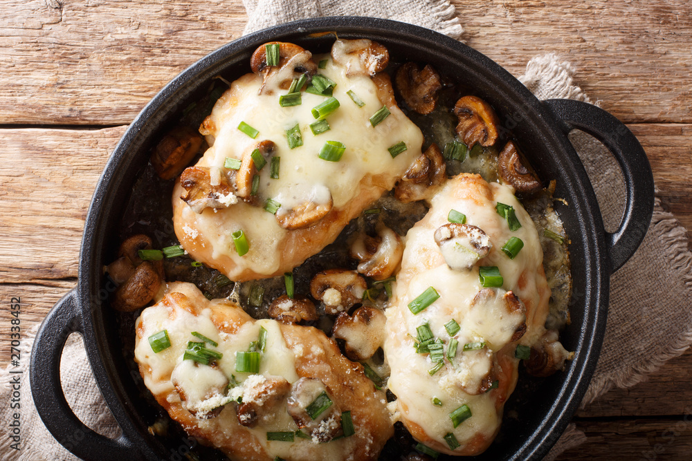 Baked chicken breast with mushrooms, green onions, mozzarella and parmesan close-up in a pan. Horizontal top view Baked chicken breast with mushrooms, green onions, mozzarella and parmesan close-up in a pan. Horizontal top view