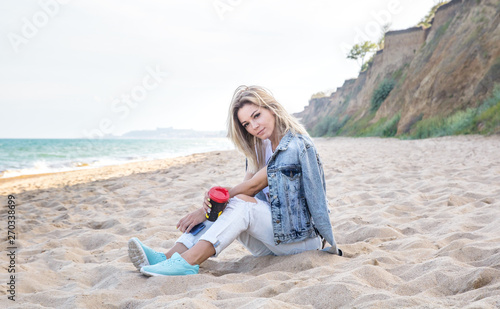 young attractive female resting on the beach with caup of coffee photo