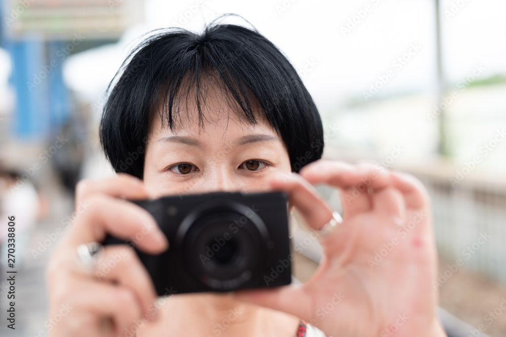 mature Asian woman using digital camera mature Asian woman using digital camera