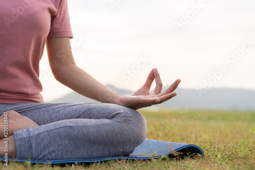 close up hand and half body of health woman sit in lotus yoga position in the morning at park. Practicing yoga makes meditation for healthy breathing  and relaxation